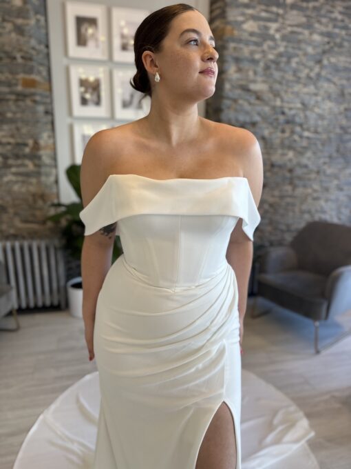 Gentry a fitted crepe wedding dress with a leg slit, rouching from the hip and a soft arm band.