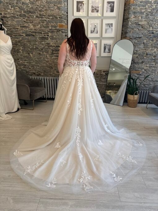 plus size bride standing in a lace a line wedding dress with a notched neckline